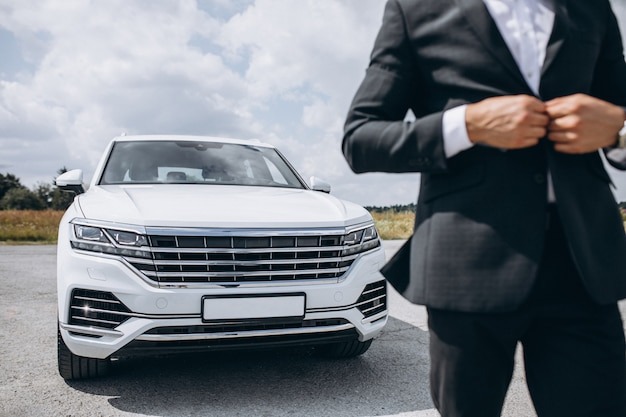 Handsome business man by the white car